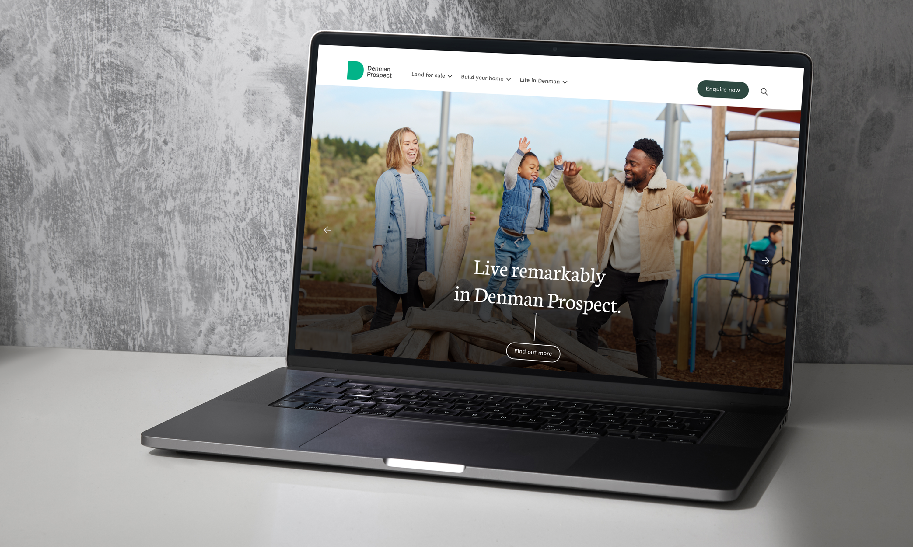 Denman Prospect homepage on a laptop showing the 'Live remarkably in Denman Prospect' hero with lifestyle photography of a family at a playground
